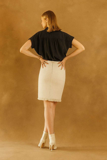 Woman wearing a black top and beige -tweed-skirt 