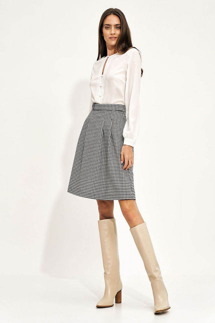 Elegant houndstooth skirt styled with a white blouse and knee-high cream boots