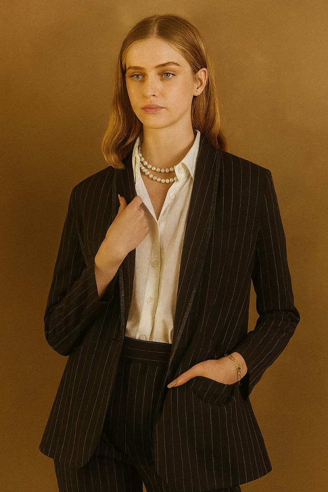 Woman wearing a black pinstripe suit with a white shirt 